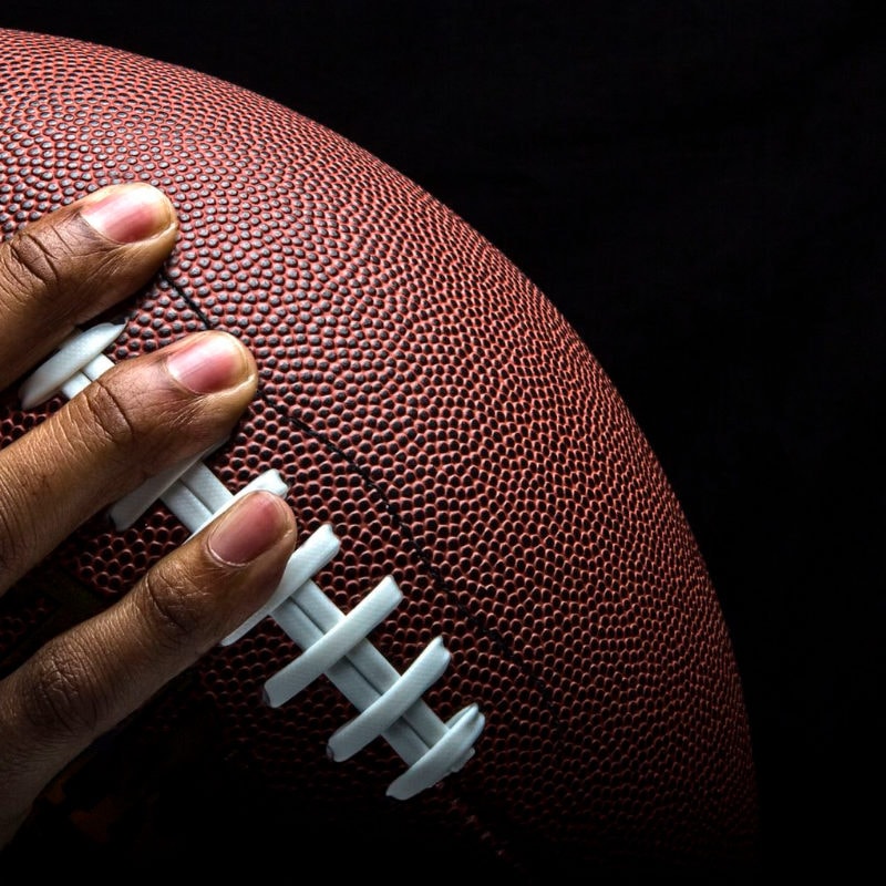 NFL player grips a football after sanitizing his hands.